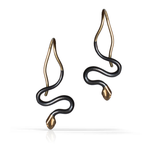 A pair of snake-shaped drop earrings with an oxidized sterling silver finish and gold tips and hooks, shown on a clean white background.