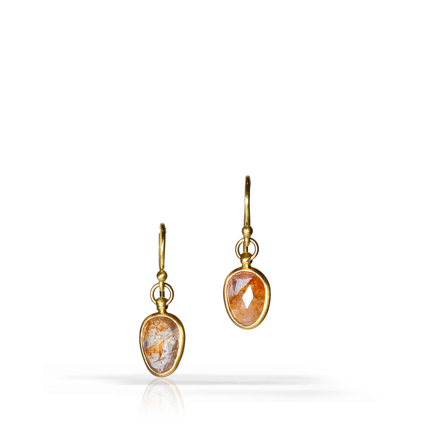 A pair of gold drop earrings with teardrop-shaped faceted gemstones, displayed on a clean white background with a soft reflection below.