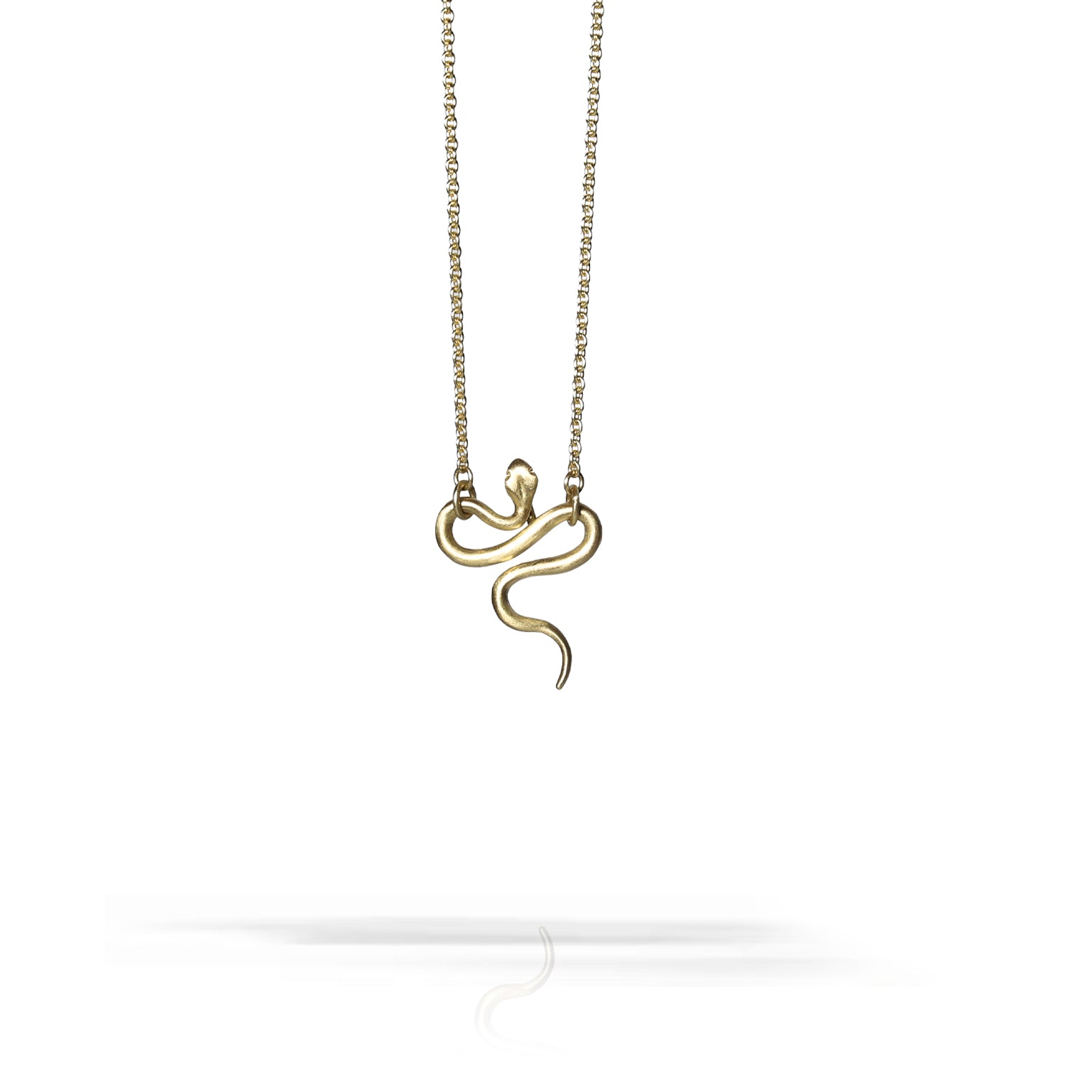 A gold-toned snake pendant necklace on a delicate chain, centered against a clean white background with a soft reflection below.