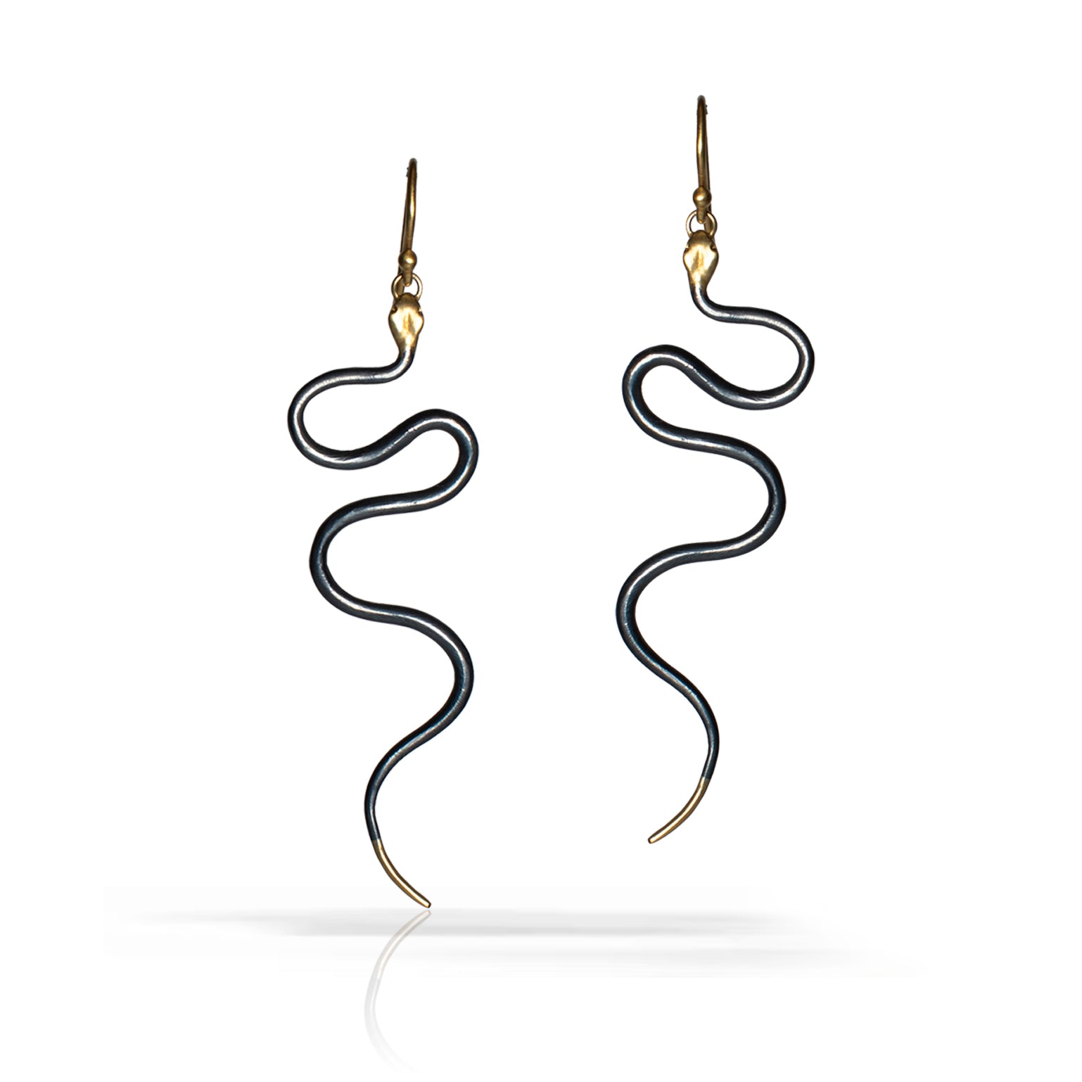 A pair of snake-shaped drop earrings with black bodies and gold-toned heads, hooks, and tips, shown on a clean white background with a soft reflection below.