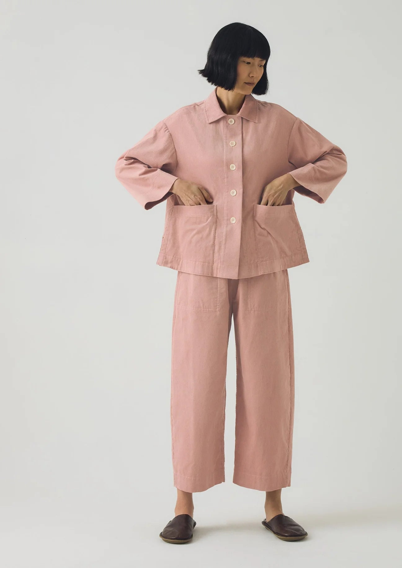 Person wearing a pink outfit with a matching jacket and pants on a white background