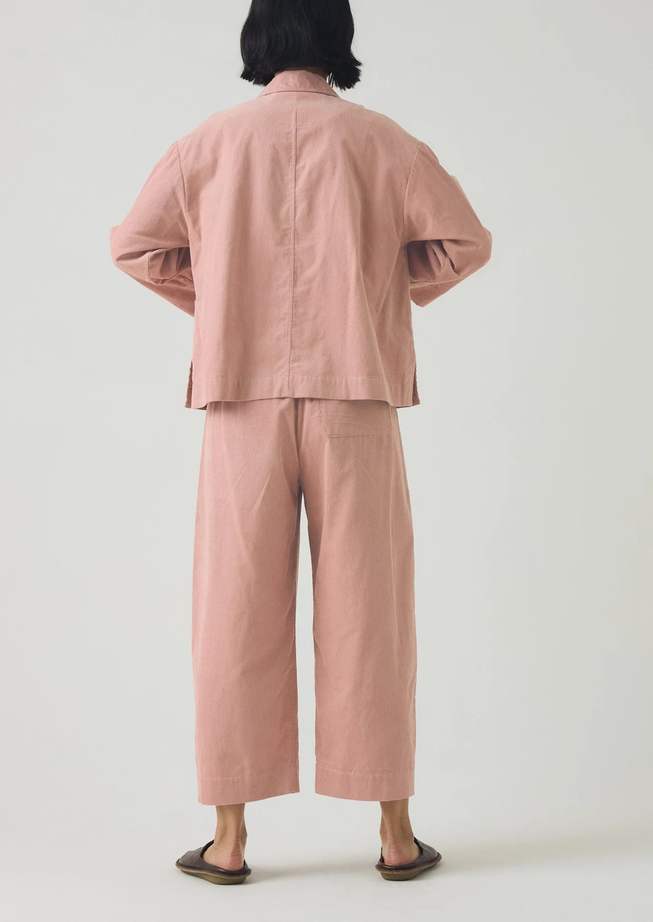 Person wearing a pink outfit with wide-leg pants on a white background