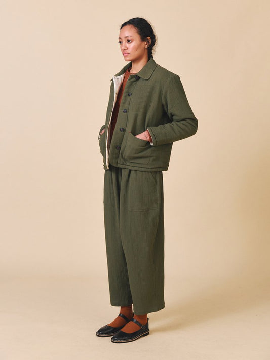 Person wearing a green outfit with a beige background
