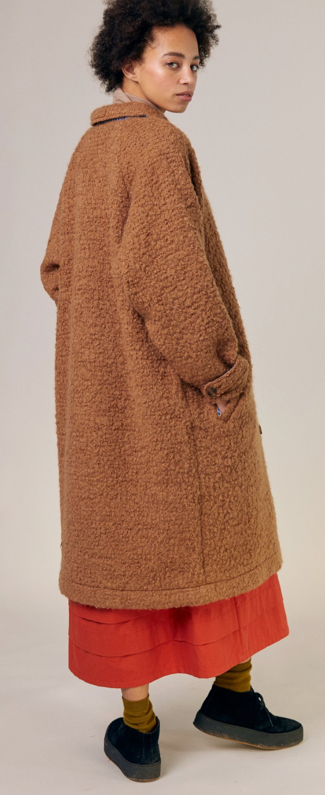 Wool Boucle knee length coat, partial back and side view with hands in pockets