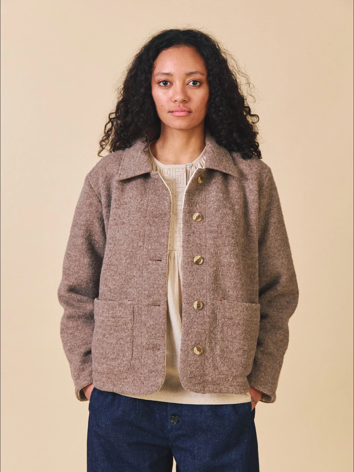 Woman wearing a brown jacket with buttons on a beige background