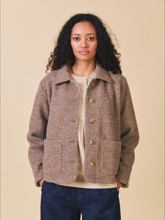 Woman wearing a brown jacket with buttons on a beige background