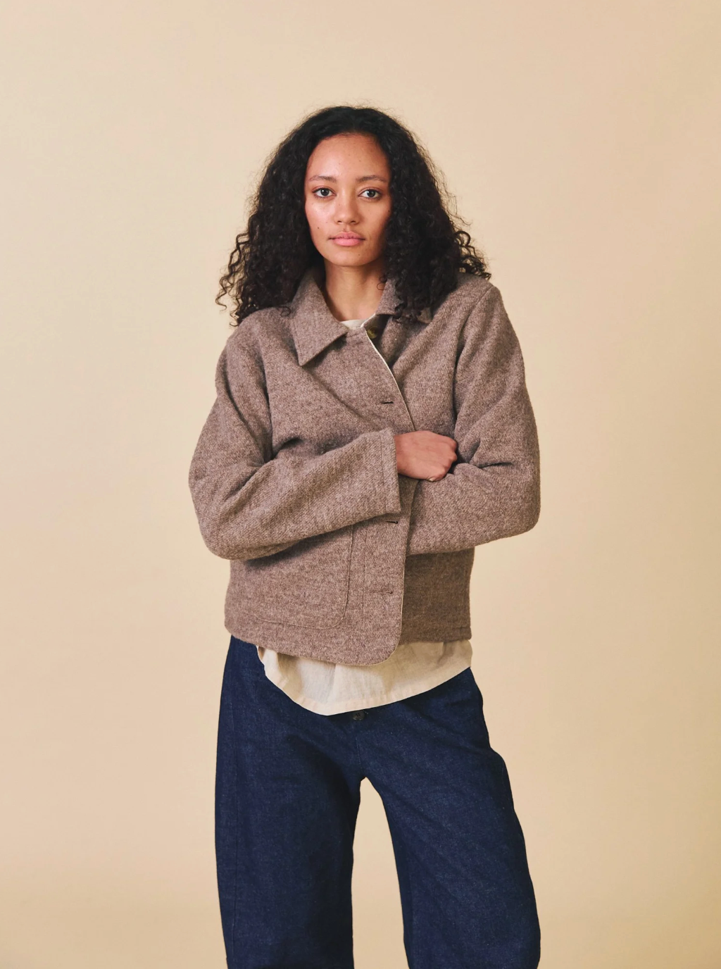 Woman wearing a brown jacket with a plain background