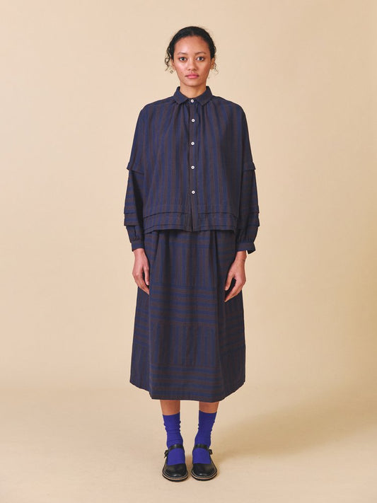 Person wearing a navy striped outfit on a beige background