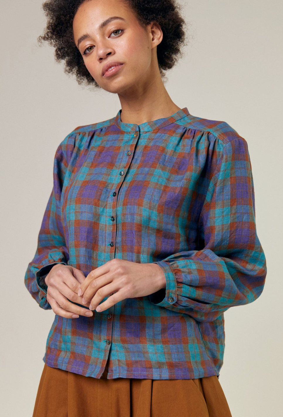 10 button front check shirt with long sleeves. gathers at the front and back yoke seams. Delicate stand collar and one button cuff opening