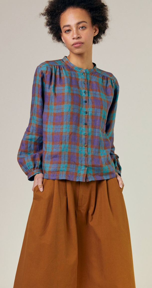 Purple/brown/turquoise check shirt fully buttoned with a gathered cinnamon color skirt 