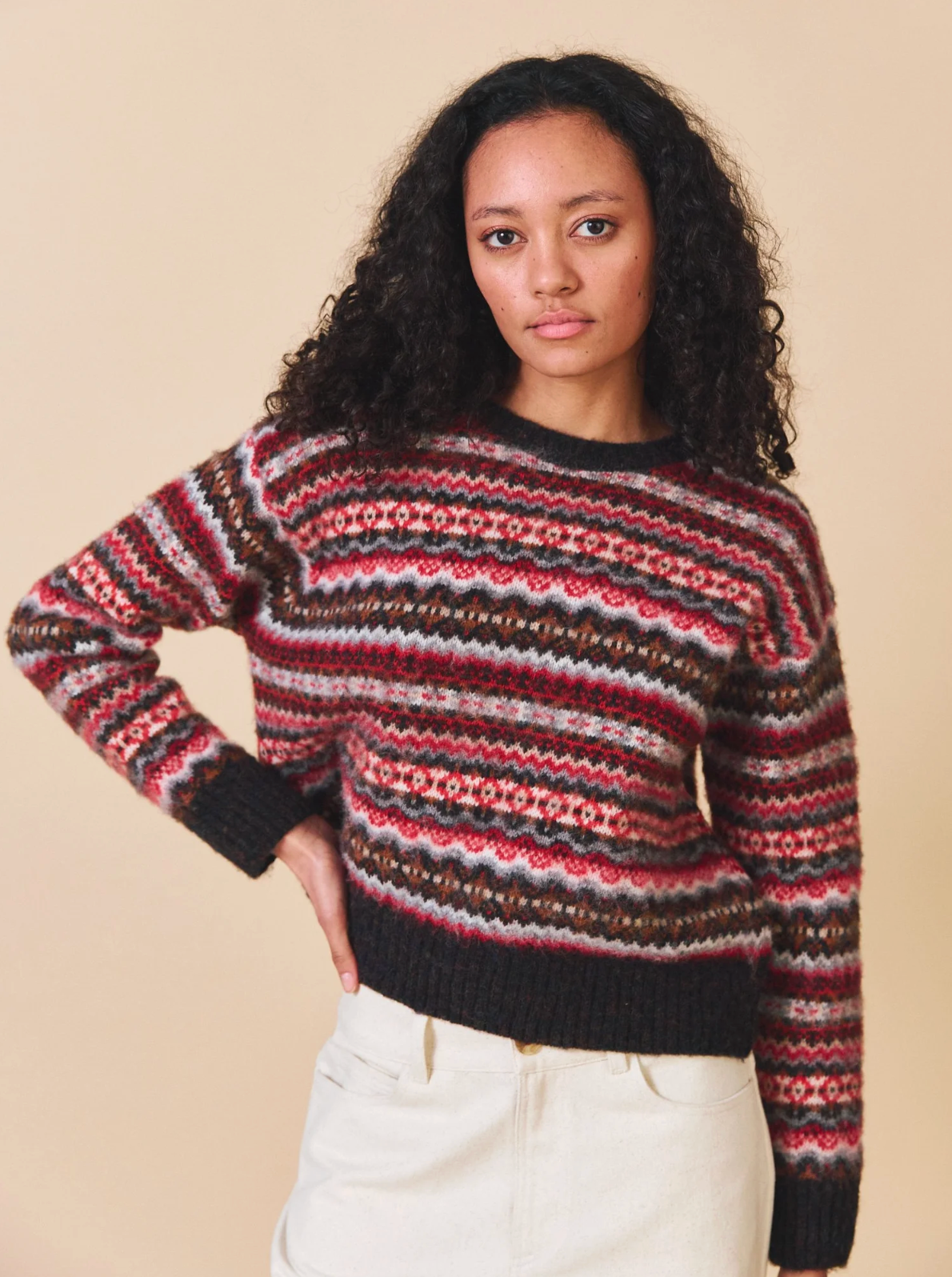 Woman wearing a patterned sweater against a beige background