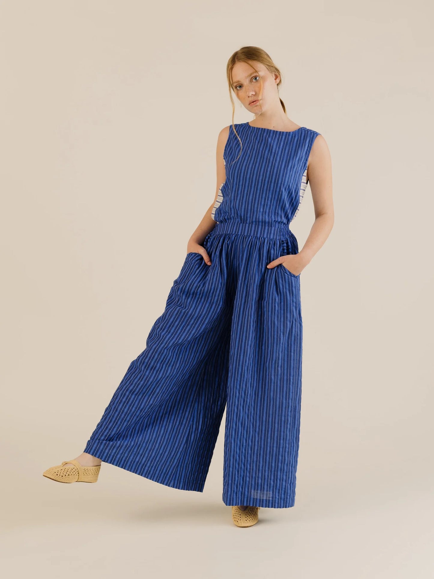 Sleeveless stripe top with matching wide leg pant. Model has hands in pockets. Light background 