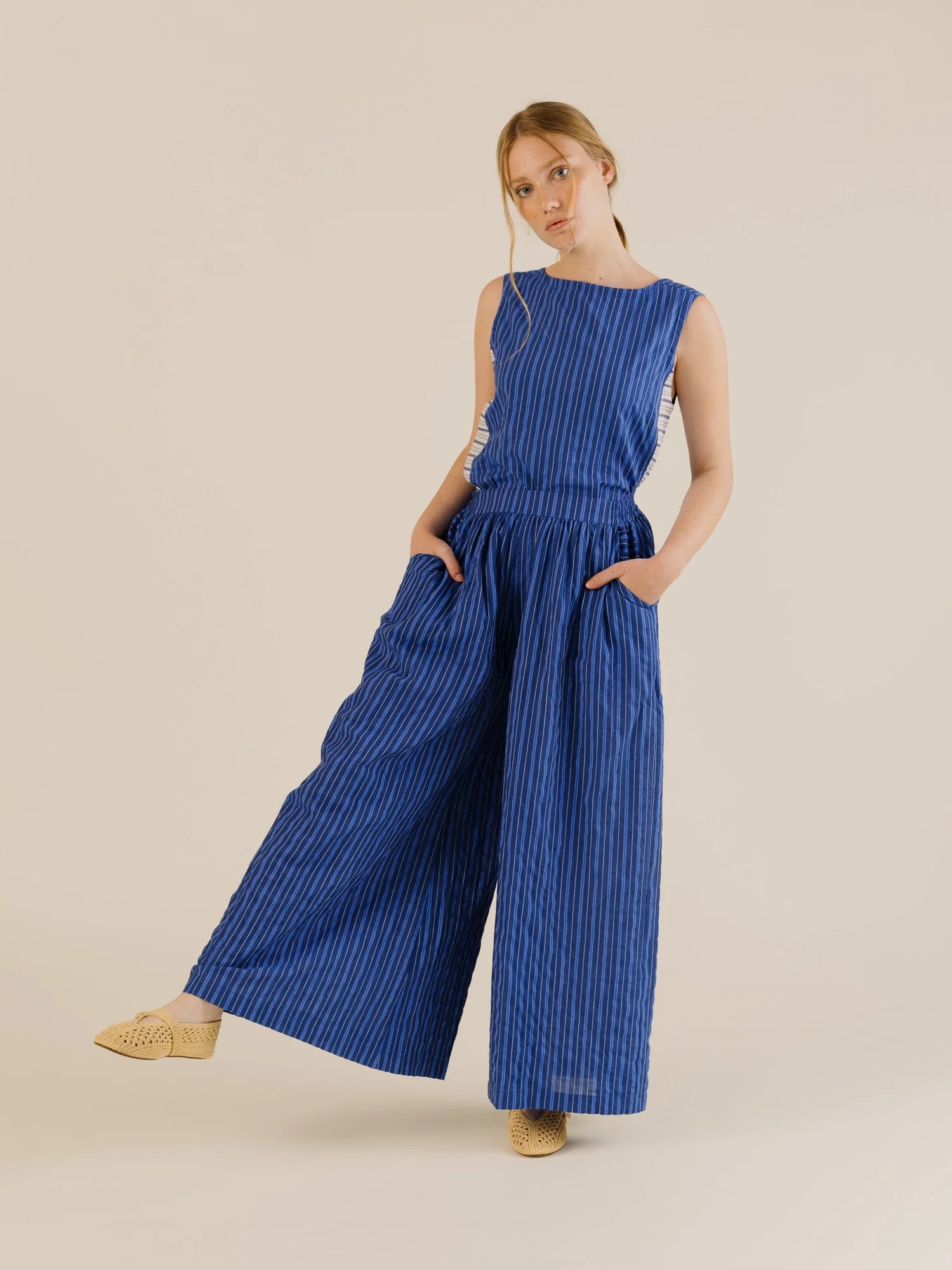 Sleeveless stripe top with matching wide leg pant. Model has hands in pockets. Light background 