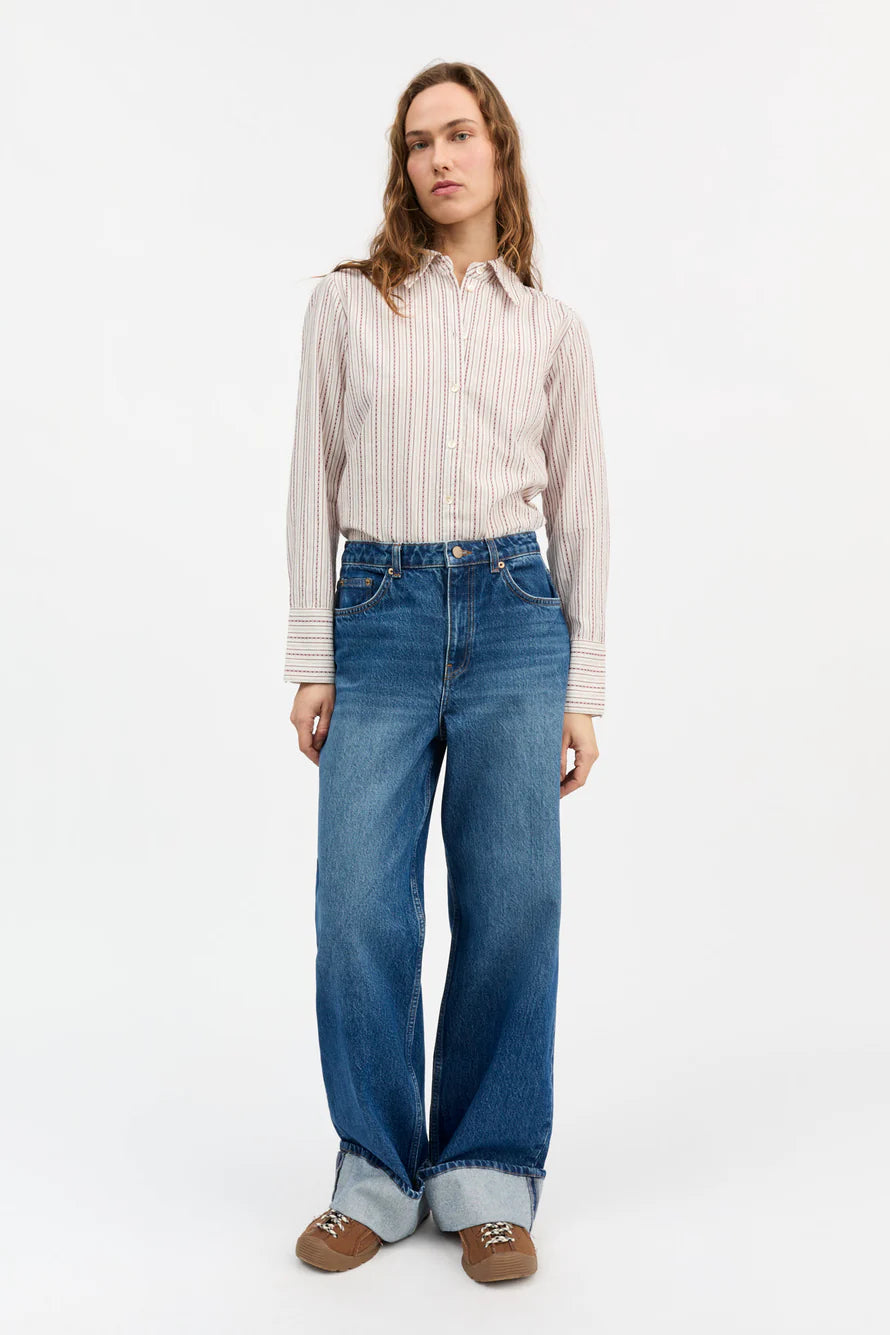 Woman wearing a striped shirt and blue jeans on a white background