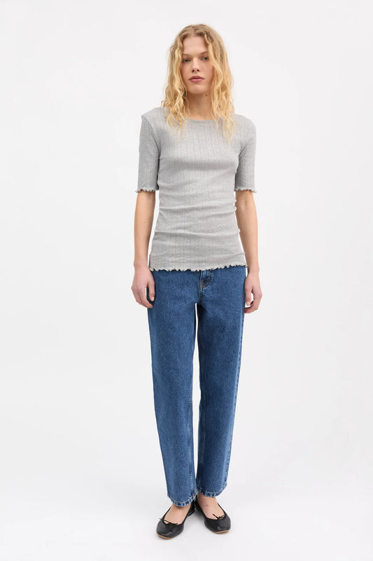 Woman wearing a gray top and blue jeans on a white background