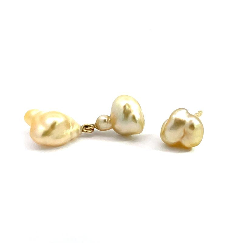 An asymmetrical pair of chamoagne-colored pearl earrings.
