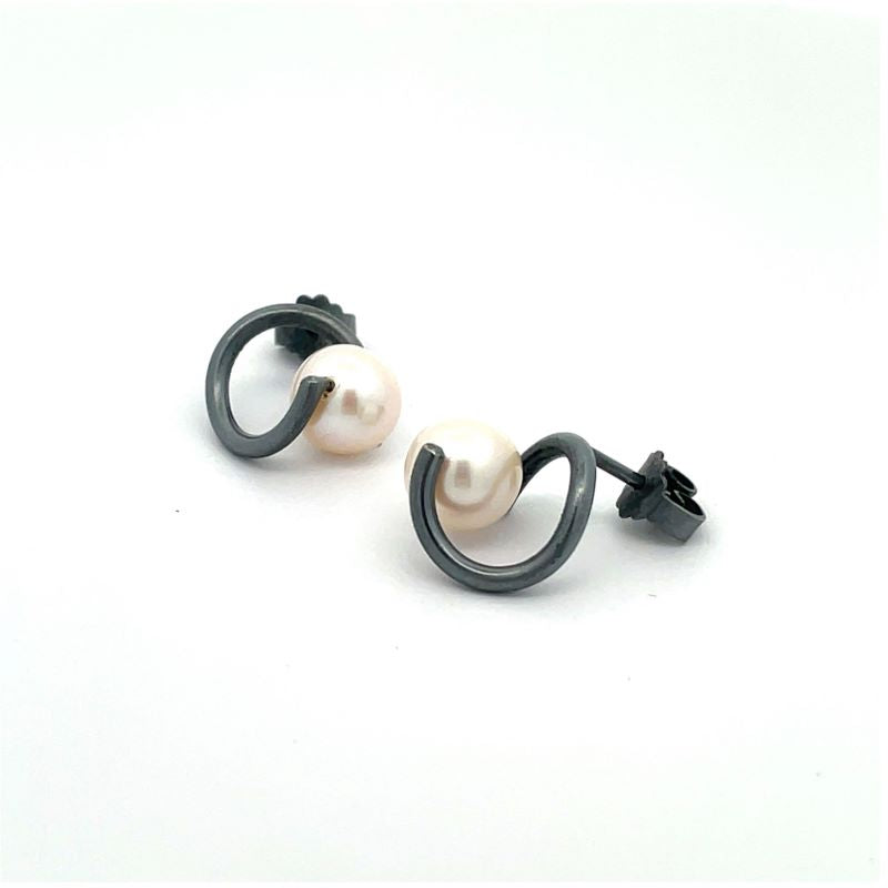 A pair of oxidized sterling silver twist earrings with a single white freshwater pearl suspended in each loop, shown on a plain white background.