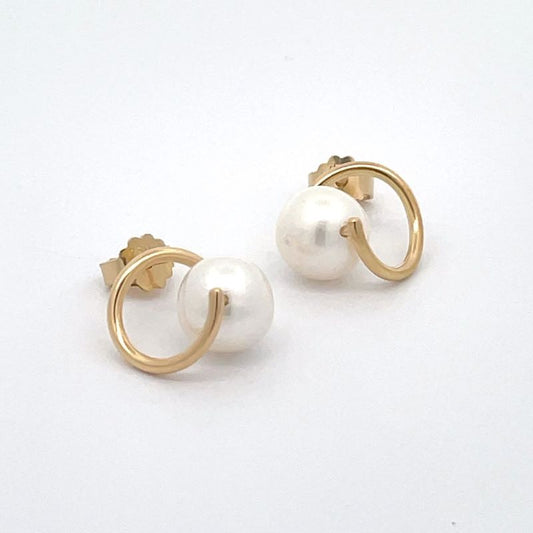 A pair of gold earrings with a single white pearl suspended in the center of each twist, shown on a plain white background.