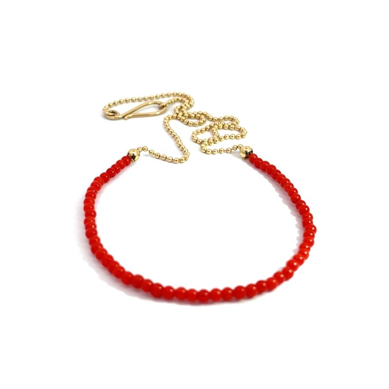 A red coral necklace with a yellow gold chain and clasp, displayed on a clean white background.