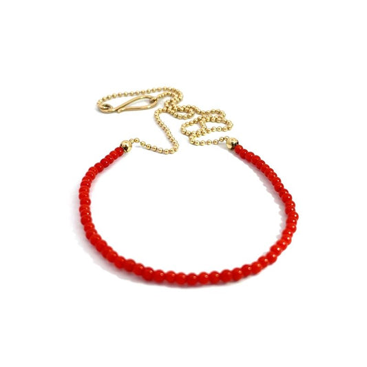 A red coral necklace with a yellow gold chain and clasp, displayed on a clean white background.
