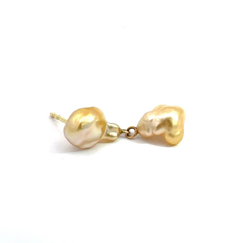 A pair of gold stud earrings featuring irregular, baroque-style freshwater pearls in a champagne-gold color, connected by a small gold chain.