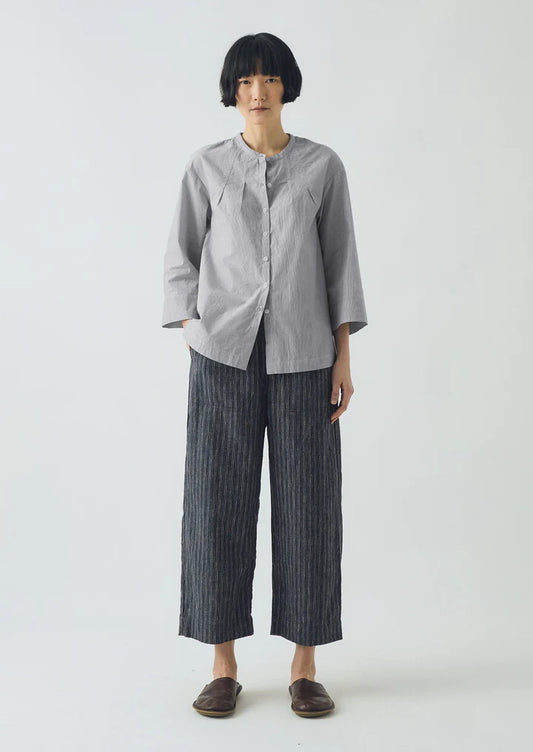 Person wearing a gray shirt and dark striped pants on a white background