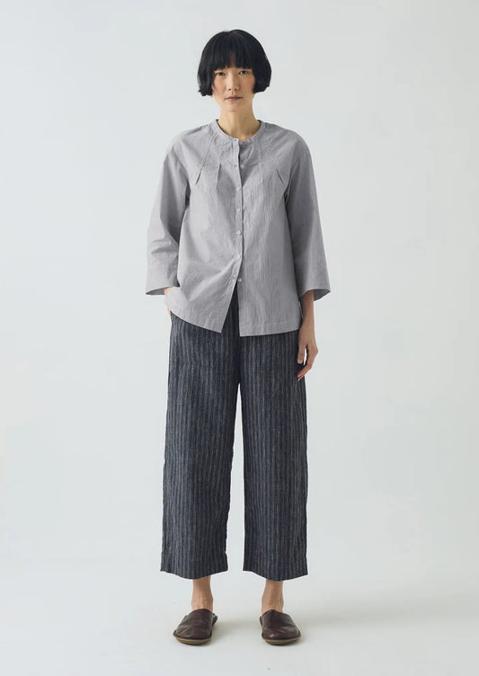 Person wearing a gray shirt and dark striped pants on a white background
