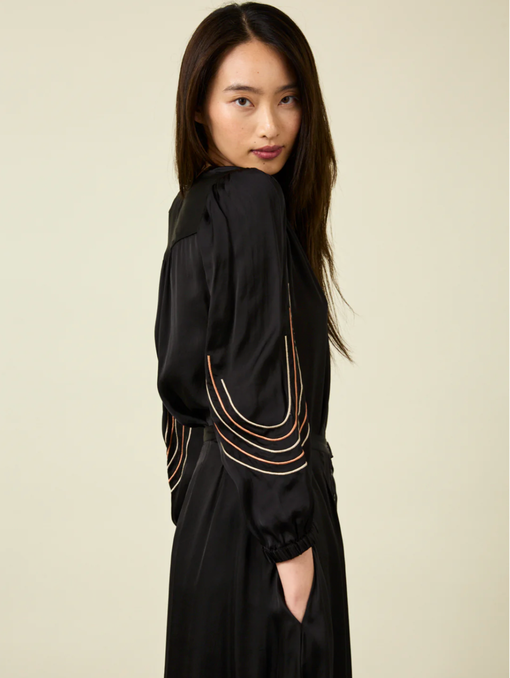 Side view of woman with long dark hair wearing black Bemberg shirt with black embroidery