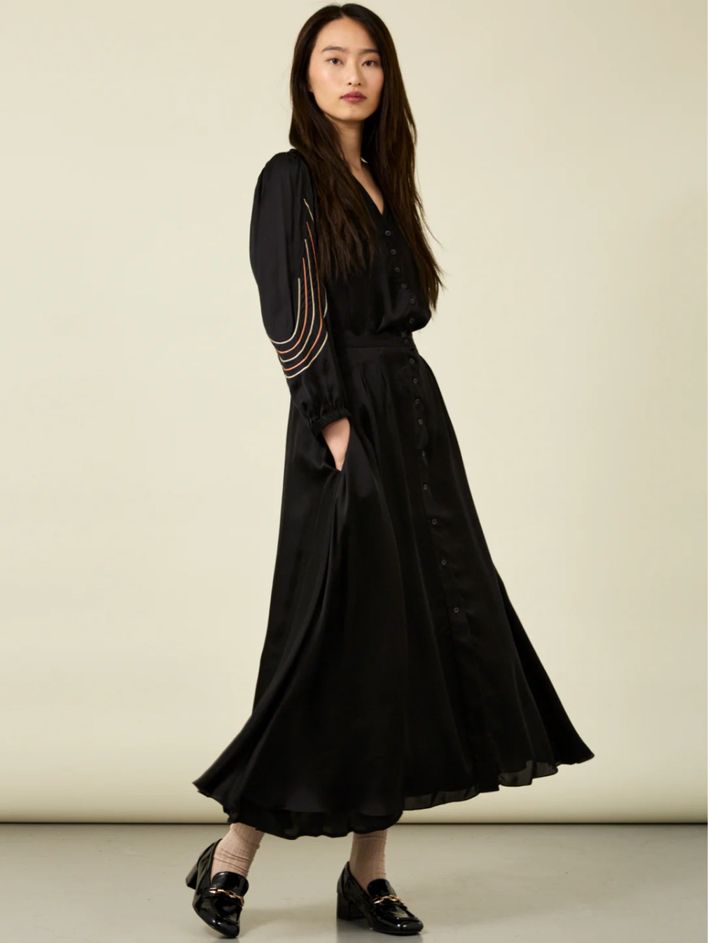 woman with long dark hair wearing black Bemberg shirt with black embroidery with matching black skirt