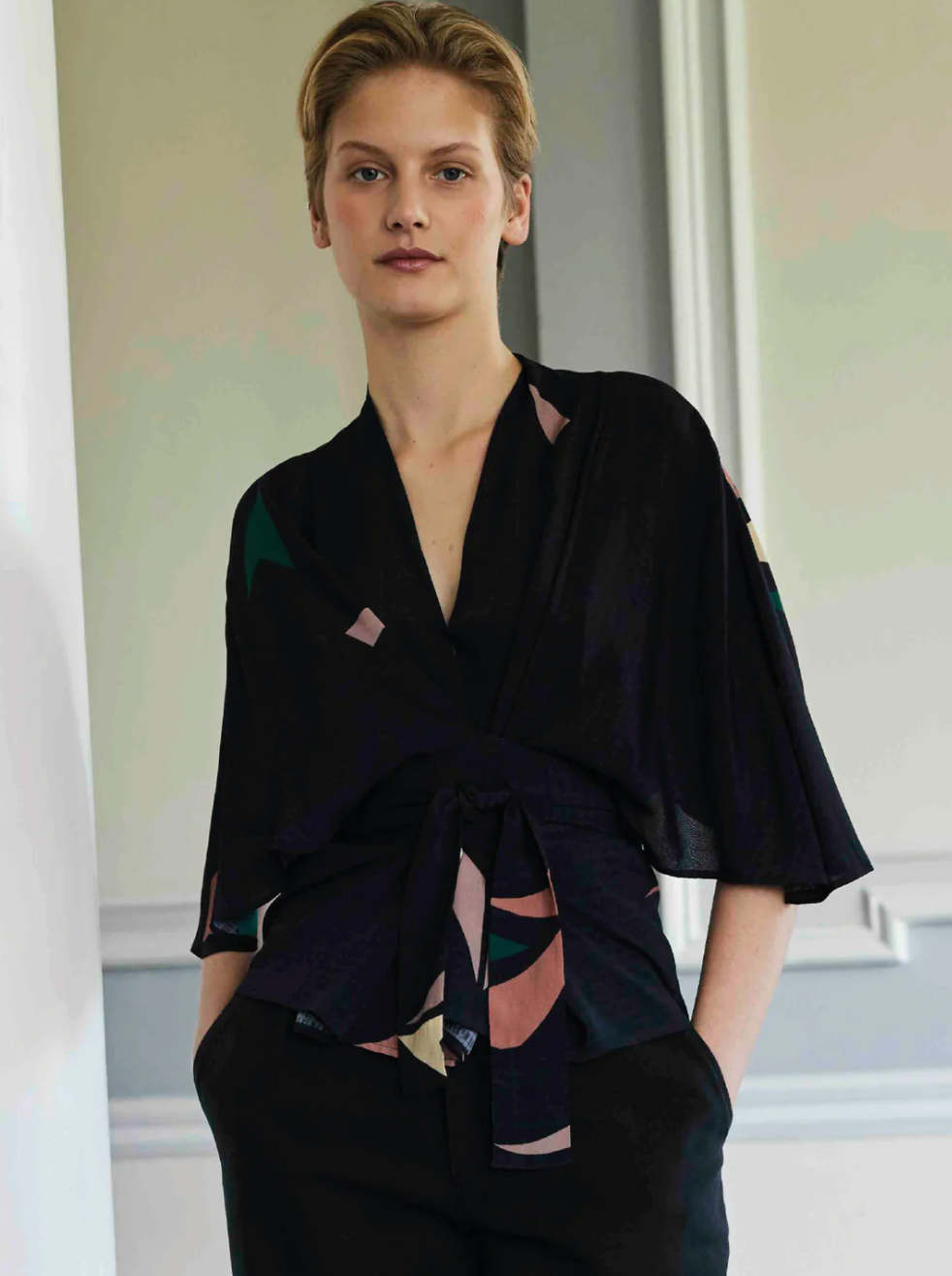 Woman wearing kimono style wrap shirt with hands in pockets
