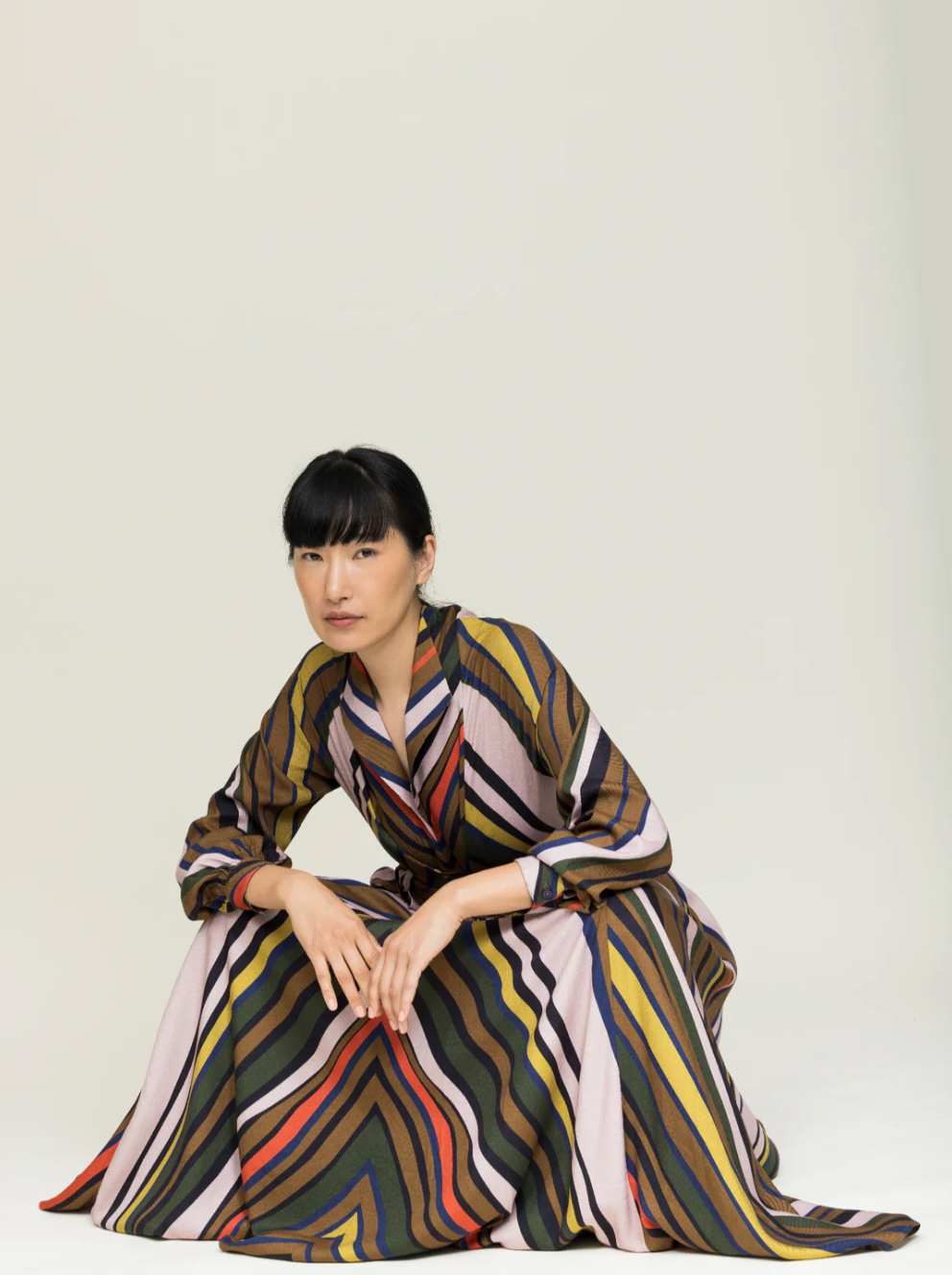 Woman wearing striped wrap dress in autumnal colors crouching