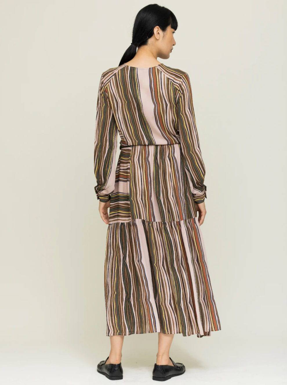 Woman wearing a long, striped dress on a white background