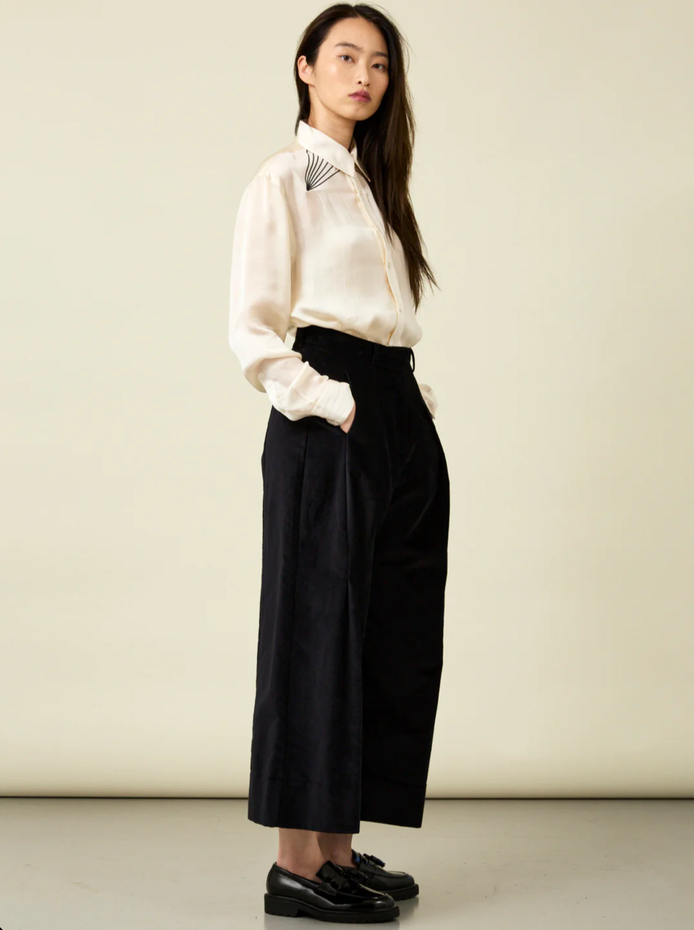 Woman wearing cream mbroidered shirt with black velvet pants