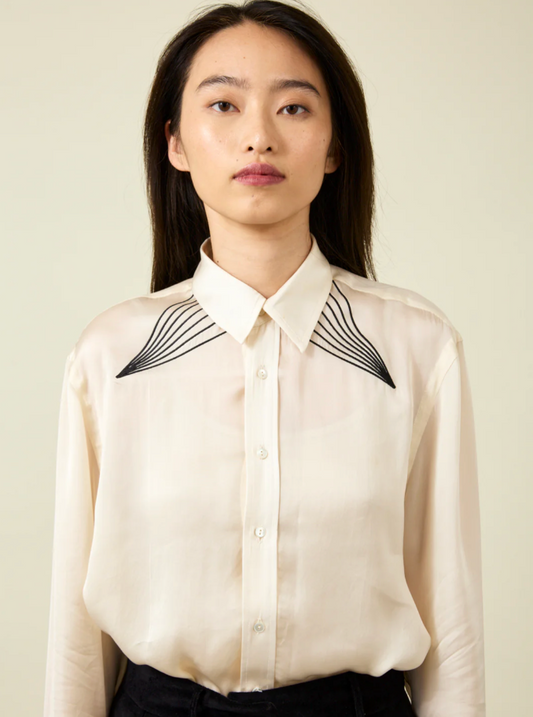 Woman wearing cream shirt with black embroidery