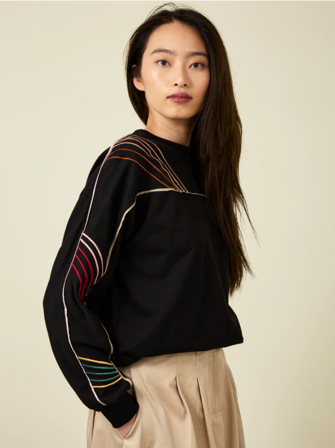 Woman wearing embroidered black sweatshirt with khaki pants