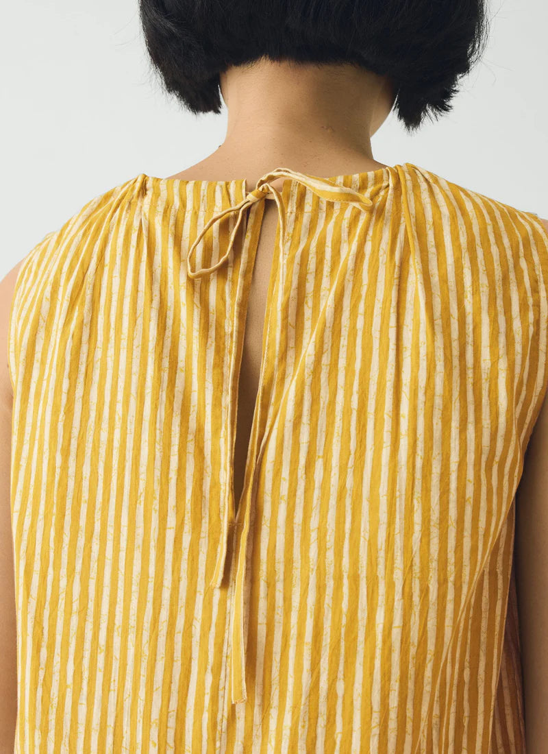 Yellow striped sleeveless top worn by a person on a plain background