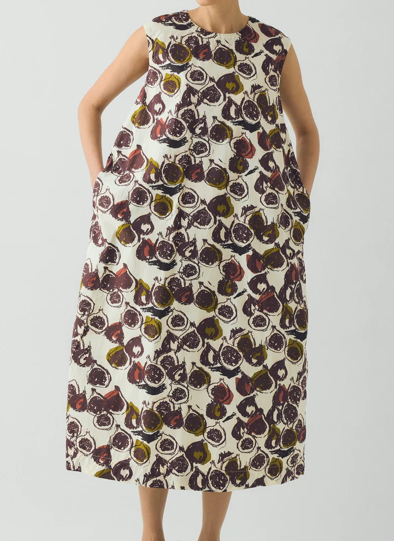 Woman wearing a sleeveless dress with a floral pattern on a plain background