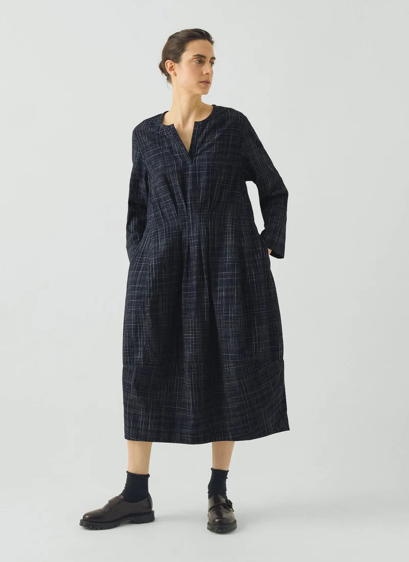 Woman wearing blue checked dress dress against a grey background