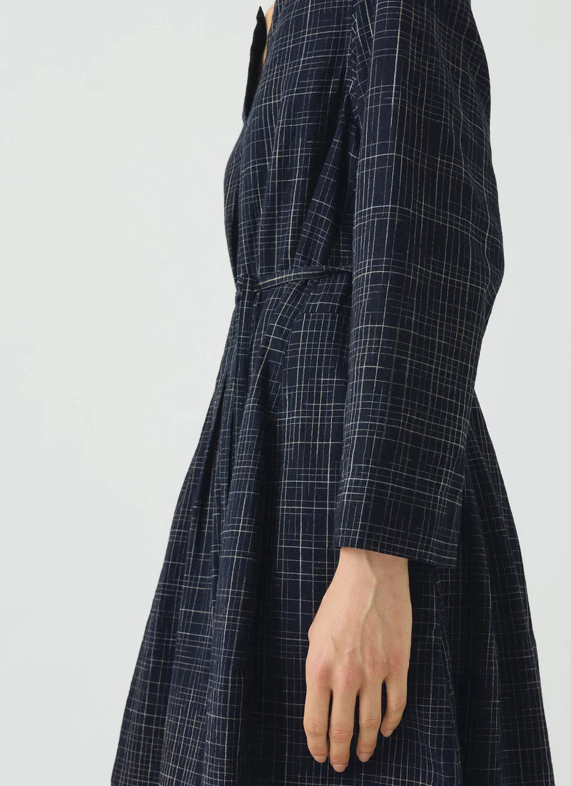 Close up detail of woman wearing blue checked dress dress against a grey background