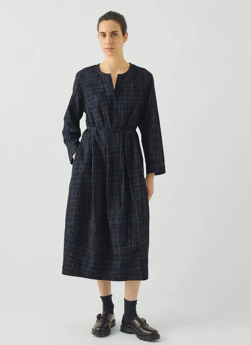 Woman wearing blue checked dress dress against a grey background