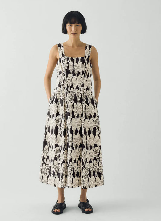 Woman wearing a black and white patterned dress with fish print on a plain background
