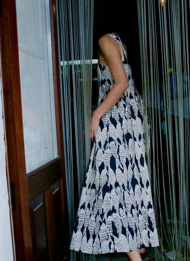 Person wearing a black and white patterned dress standing in front of a glass door.
