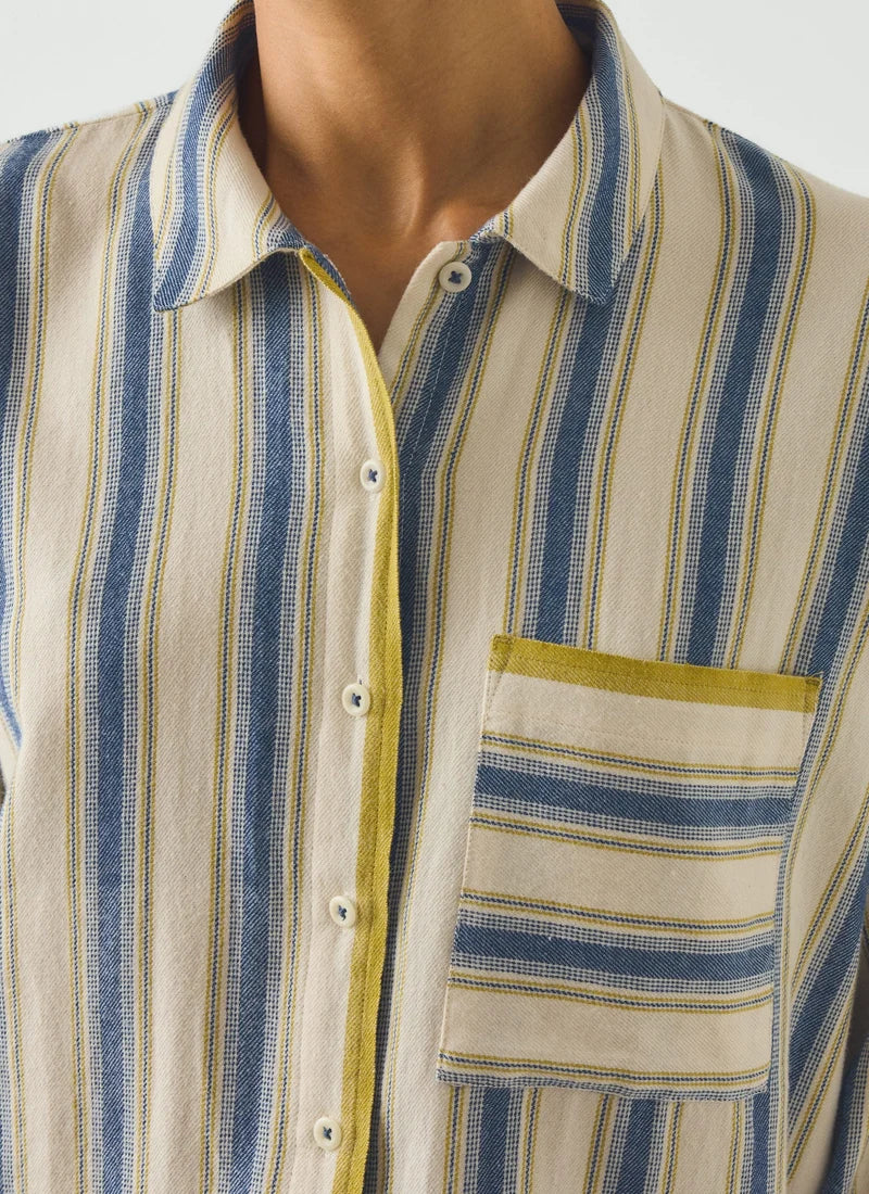 A model wearing a pajama set with blue and cream vertical stripes and a gooseberry-colored trim.