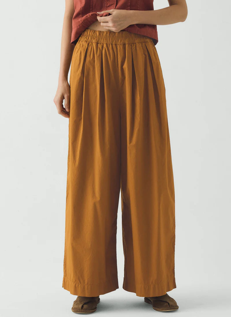 Person wearing mustard yellow wide-leg pants on a white background