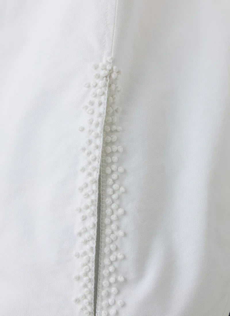 A close-up photo of french knot embroidery on a white shirt.