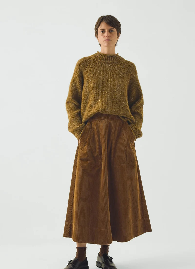 A model wearing a soft brown sweater and a golden amber corduroy skirt.