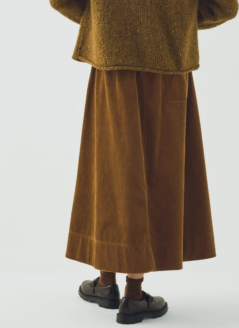 A model wearing a soft brown sweater and a golden amber corduroy skirt.