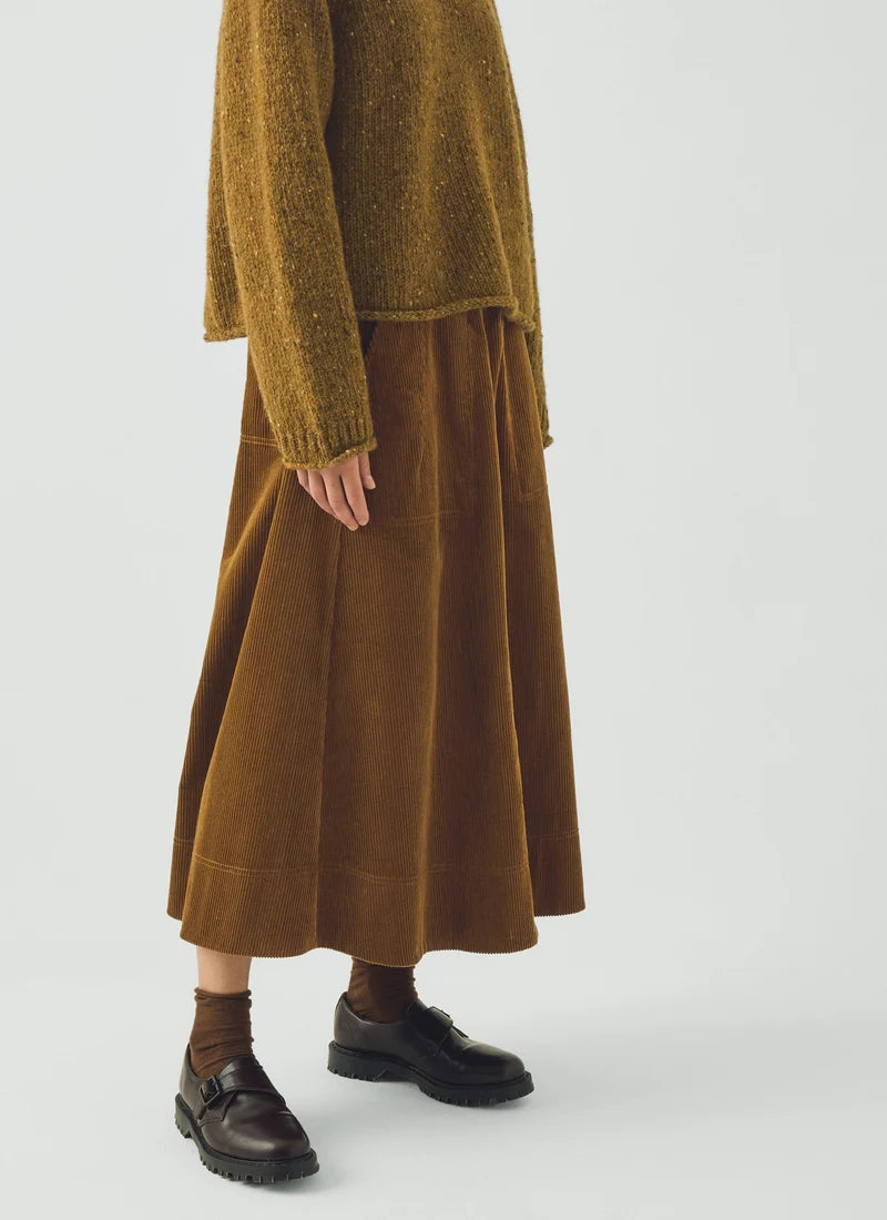 A model wearing a soft brown sweater and a golden amber corduroy skirt.