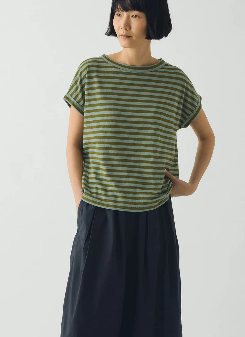 Person wearing a green and white striped shirt and dark blue pants on a white background