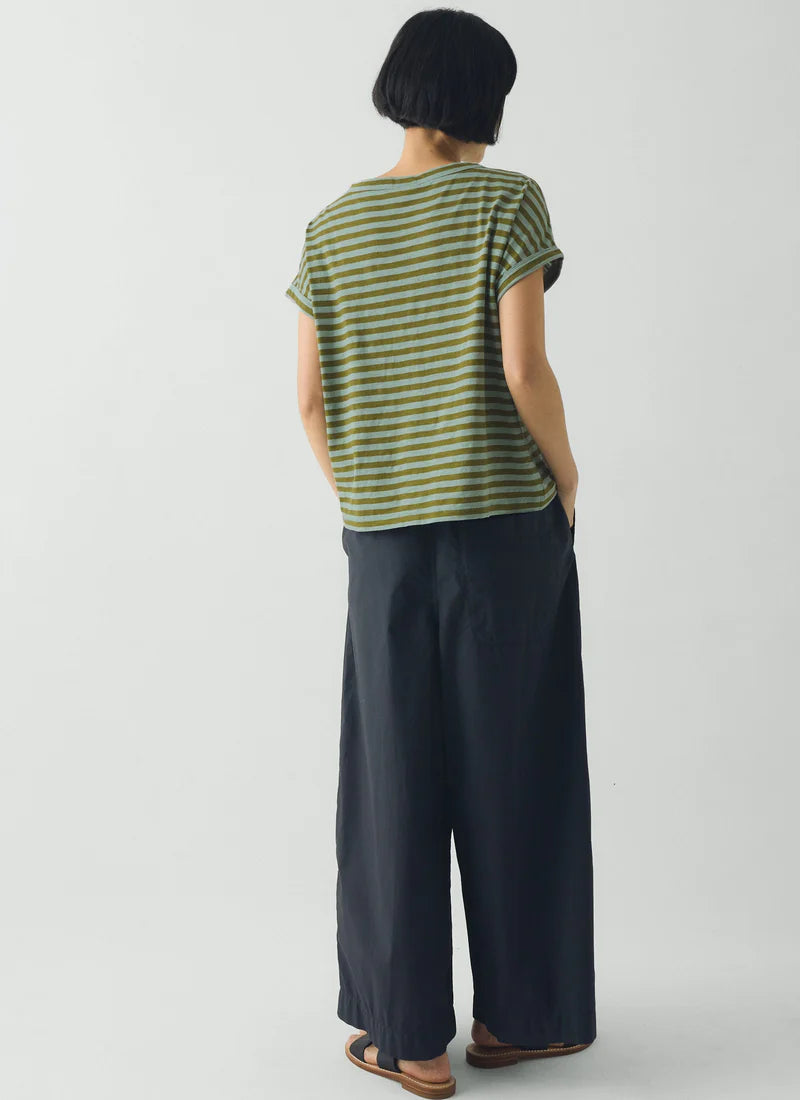 Person wearing a green and white striped shirt and dark blue pants on a white background